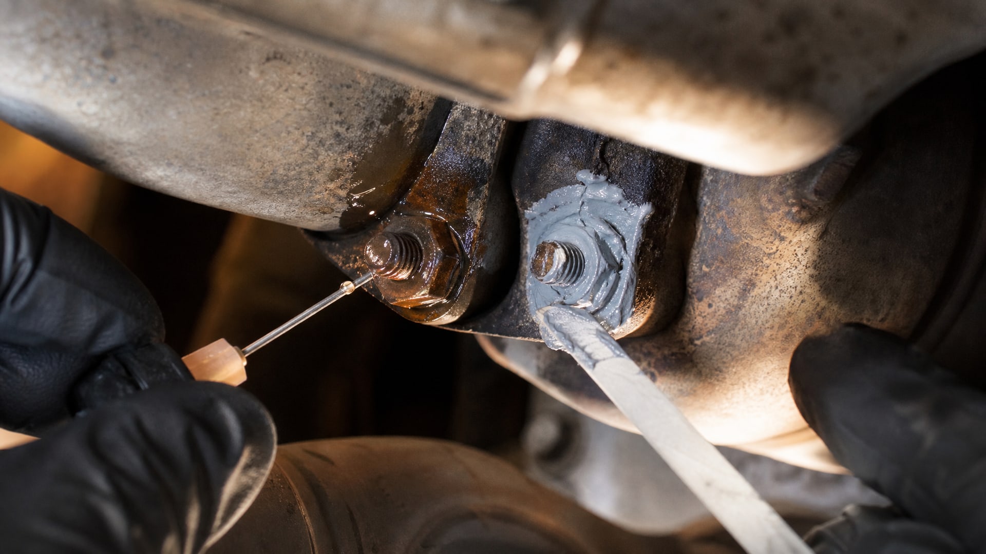 Ржавый болт на глушителе, одна сторона которого обработана WD40, а другая – густой антизадирной смазкой.