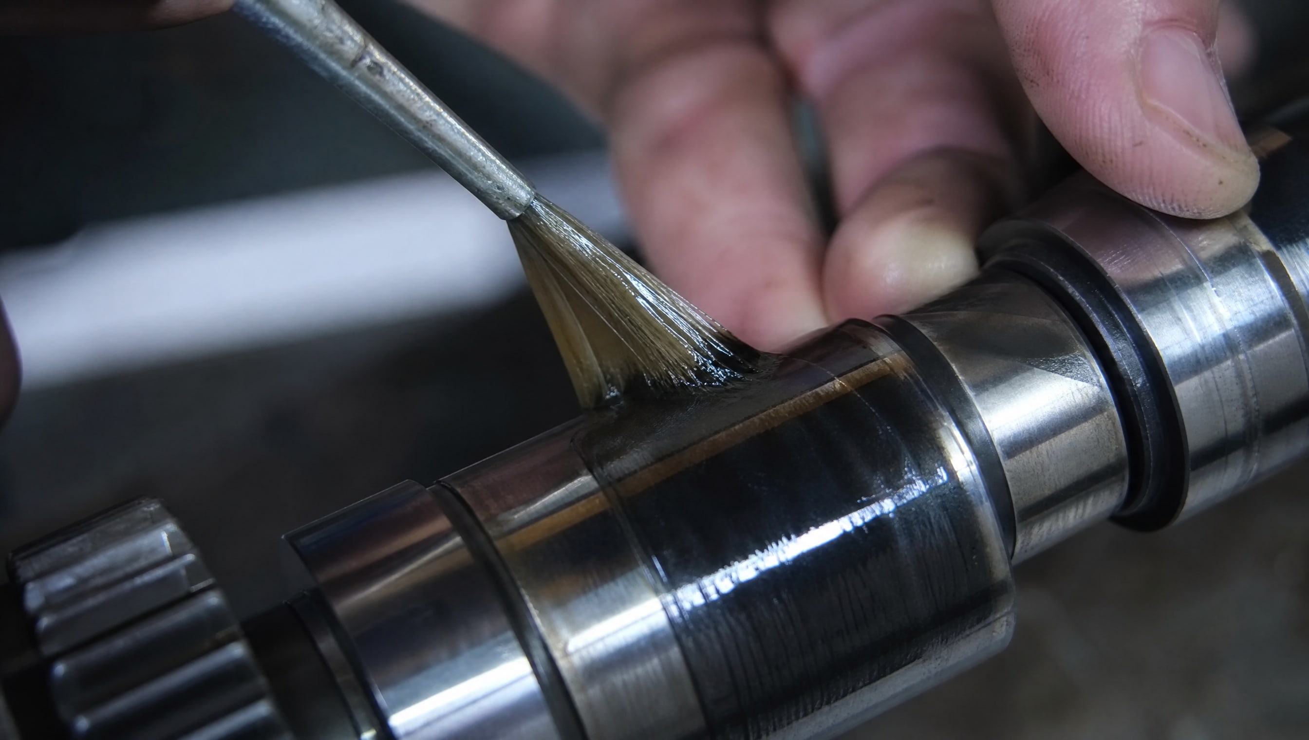 Темная пленка дисульфида молибдена на металле с тонким слоем PTFE, видна толщина слоя покрытия.