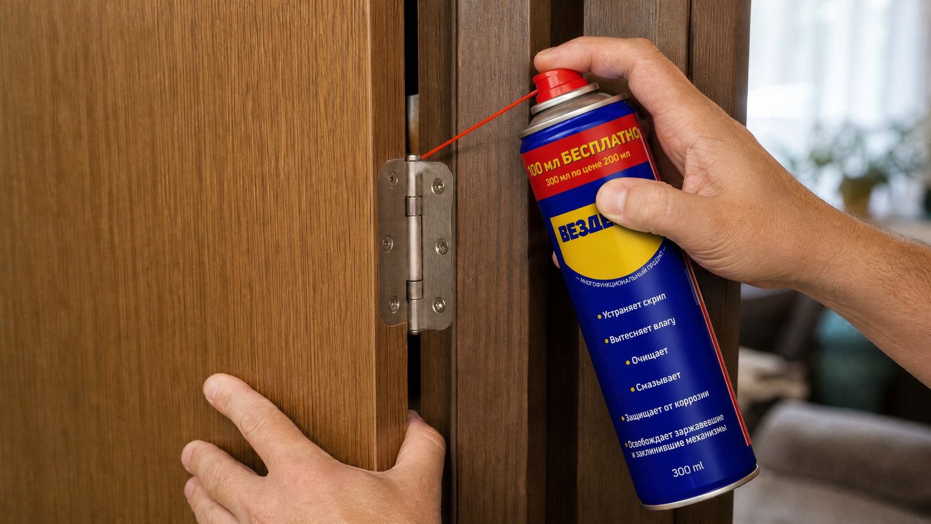 Рука в перчатке наносит универсальную смазку WD-40 на петли двери.