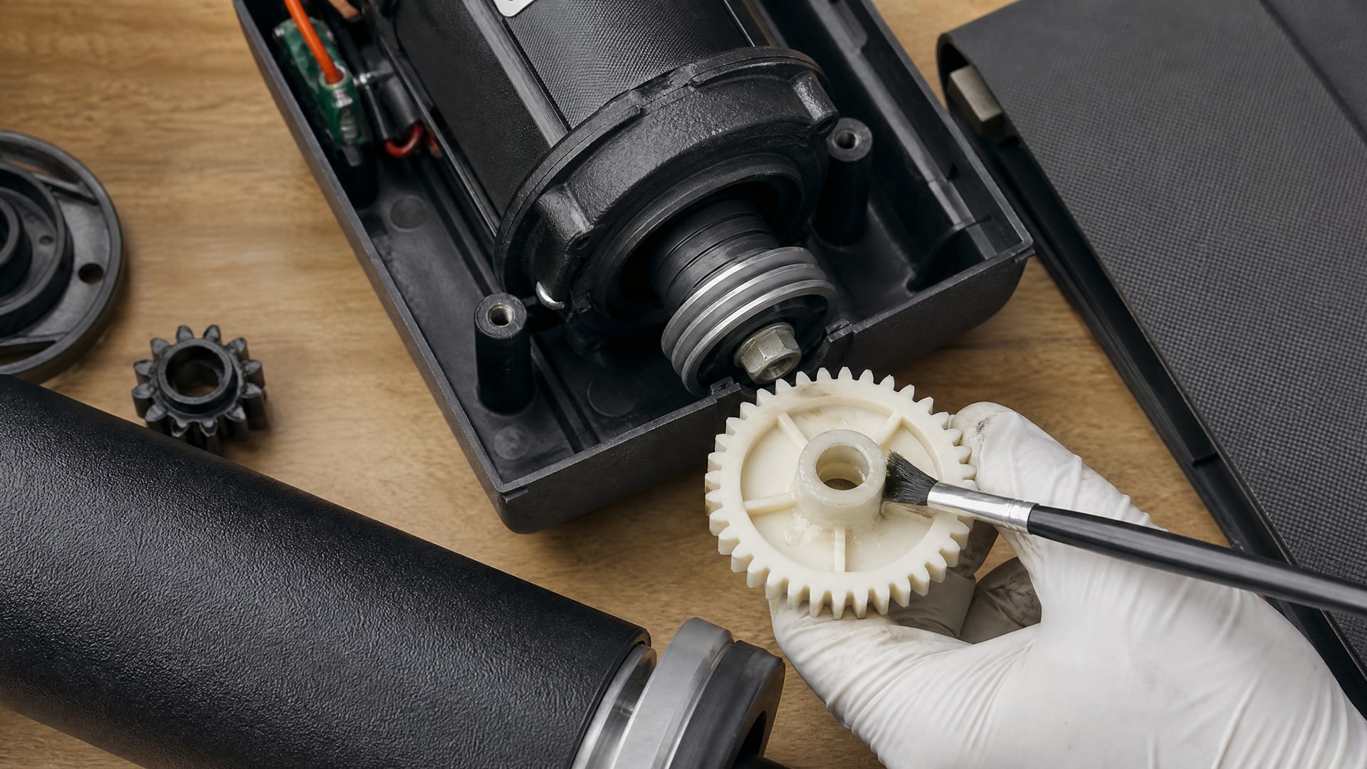 На верстаке лежат детали беговой дорожки с тонким слоем wd-40 на шестеренке.
