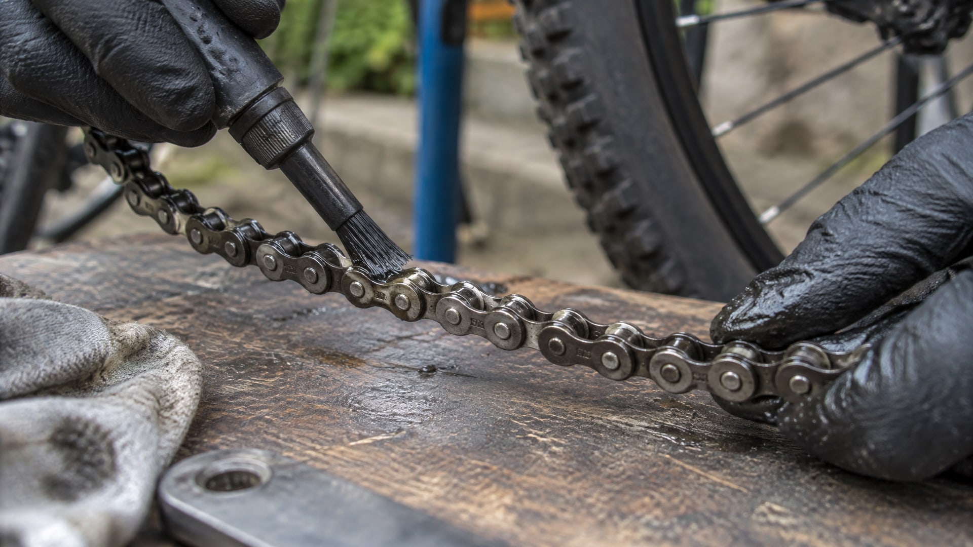Свежий слой прозрачной WD40 равномерно покрывает звенья грязной велосипедной цепи.
